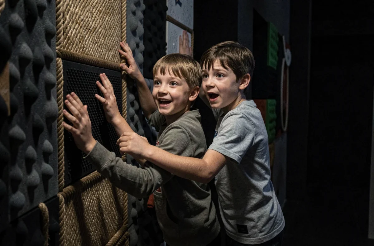 Enfants explorant un parcours sensoriel dans le noir au SENSAS de Grenoble